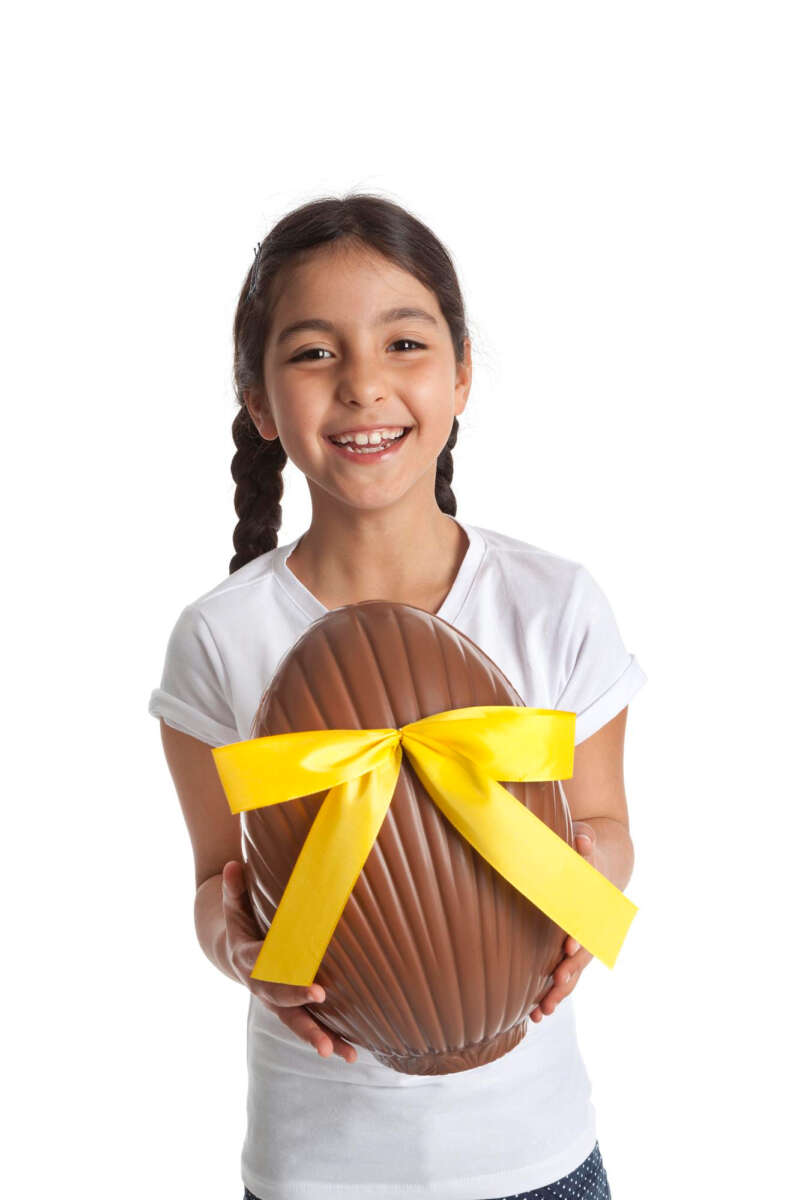 Menina feliz segurando um grande ovo de páscoa de chocolate.